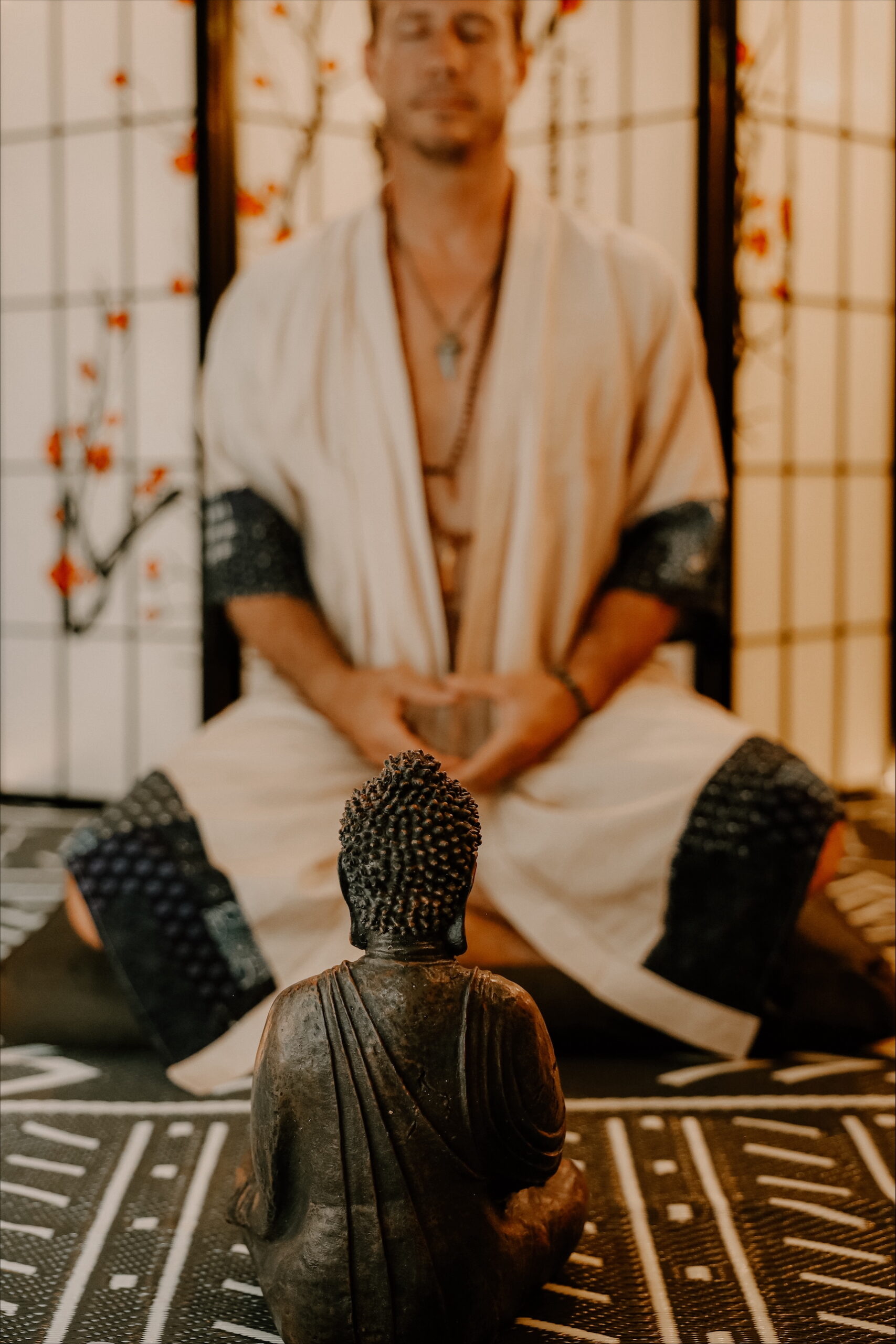 Rick sitting in meditation behind a small Buddha statue